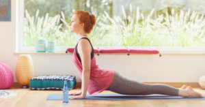 Egy nő jógázik világos szobában, előtte vizespalack