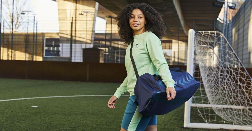Egy nő futballpályán viszi a sporttáskáját