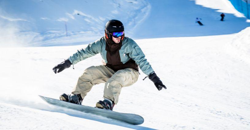 Egy snowboardos lesiklás közben látható havas pályán