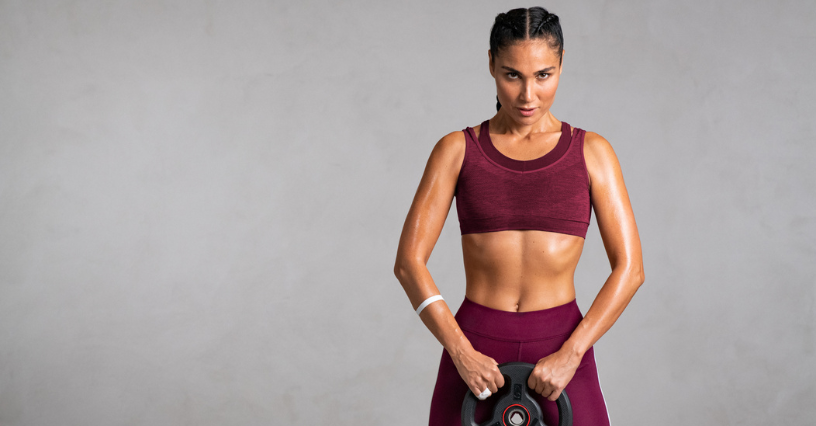 Nő edzőruhában súlyzót tart