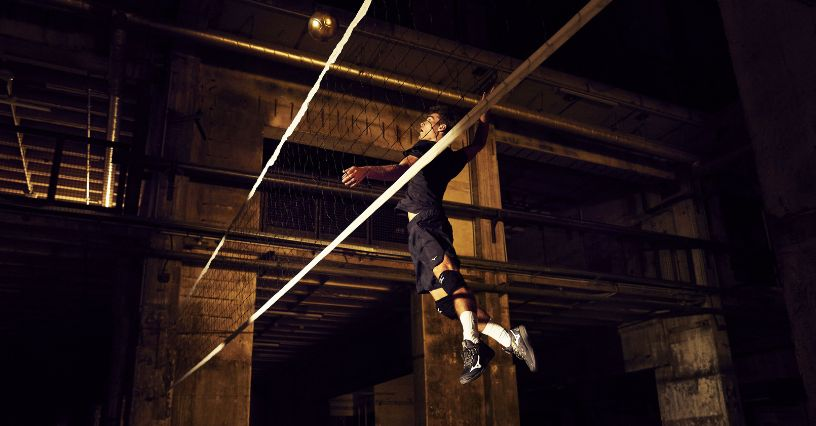 Egy sportoló ütésre készül a röplabda hálónál