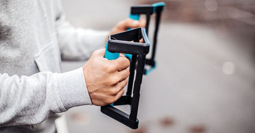 Egy ember tart fekvőtámasz kereteket a kezében az edzéshez