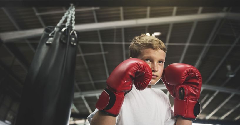 Egy gyerek piros bokszkesztyűben gyakorol