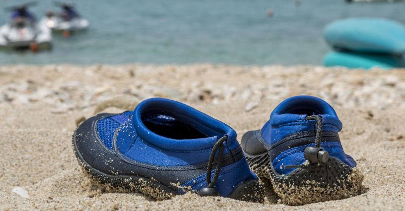Kék vízi cipők a homokos tengerparton gyerekek számára
