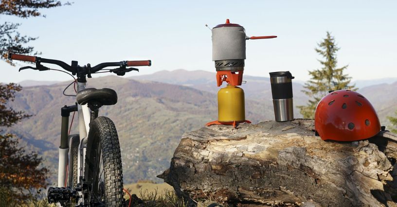 Kerékpár és kempingfelszerelés egy hegyvidéki táj előtt látható