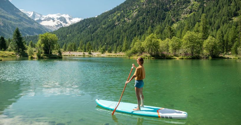 Egy ember evez egy SUP deszkán egy tó közepén